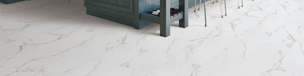 A kitchen island with a dark teal finish stands on a white marble-patterned vinyl tile floor.